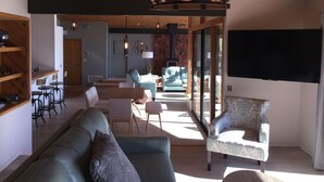 Un vaste espace de vie doté d’un plafond en bois, d’un canapé, de deux fauteuils, d’une table basse et d’une cheminée.