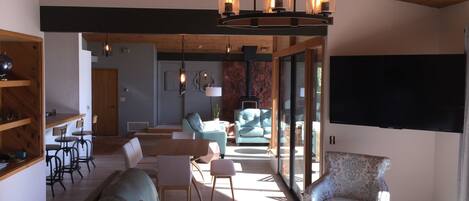 A spacious living area with a wooden ceiling, a sofa, two armchairs, a coffee table, and a fireplace.