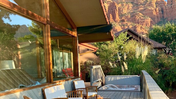 Une terrasse en bois avec des sièges d’extérieur, un foyer et une vue sur un paysage montagneux.
