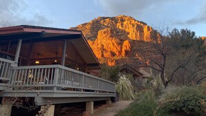 Un bâtiment doté d’une terrasse en bois, avec une montagne en arrière-plan.