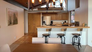 Une cuisine moderne dotée d’un îlot central, de tabourets de bar et d’une table à manger.