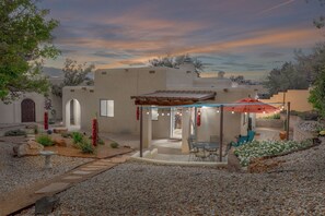 A patio area with a pergola, outdoor seating, and a view of a desert landscape.