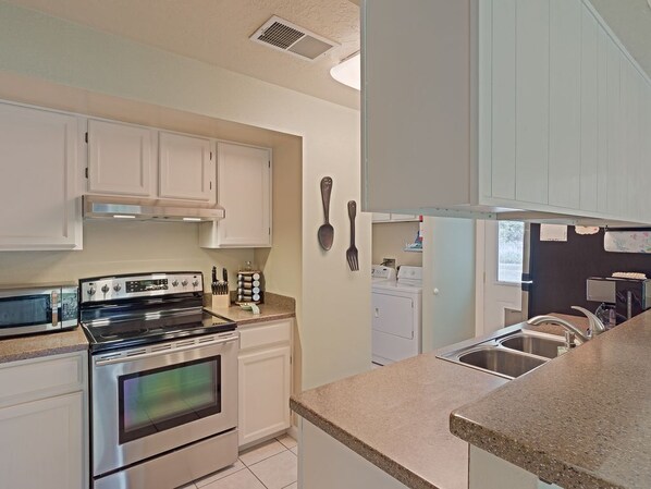 A kitchen with stainless steel appliances, white cabinetry, and a granite countertop.