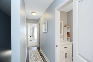 A hallway with a patterned rug, a white cabinet with drawers, and a framed picture on the wall.