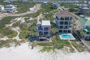 A multi-story beachfront property with a swimming pool, multiple balconies, and a beach access path.