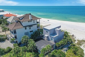 A beachfront property with a large house, a covered patio, and a view of the ocean.