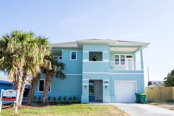 A two-story house with a light blue exterior, a front porch, and a garage. - 1 blk to the beach. 3 bdrm/3.5 bath, beach items, longboard, pickleball closeby (Cocoa Beach)
