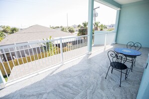 A balcony with a white railing, a tiled floor, and a table with two chairs. - 1 blk to the beach. 3 bdrm/3.5 bath, beach items, longboard, pickleball closeby (Cocoa Beach)