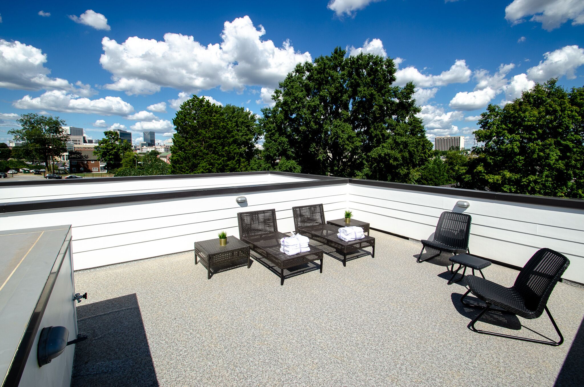 A rooftop terrace with outdoor furniture, a water feature, and a city skyline view.
