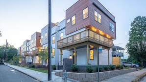 A modern multi-story residential building with a prominent corner balcony, a fire hydrant, and a well-maintained sidewalk. - NEW Modern House with Roof Deck of Atlanta Skyline (Atlanta)