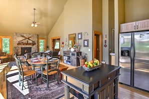A spacious kitchen with a large island, a stone fireplace, and a modern stainless steel refrigerator.