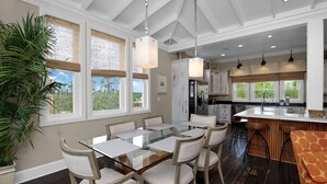 A spacious kitchen with a central island, large windows, and a dining area with a glass table and chairs. - Gulf View, Large Home with Elevator, and Easy Beach Access ~ Sammys Old Place (Indian Pass)