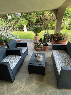 An outdoor patio area with wicker furniture, potted plants, and a staircase leading to an upper level. - A VALE OF HOUSE - for rural holiday accommodation (Pistoia)