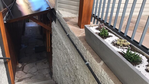 A narrow outdoor staircase with a metal handrail, leading to a wooden deck area. - Casa Gramado Encantos (Gramado)