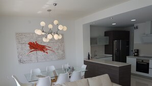 Una cocina moderna con una isla central, armarios blancos y electrodomésticos de acero inoxidable.