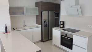 Una cocina moderna con un refrigerador de acero inoxidable, un horno empotrado y una cafetera sobre la encimera.