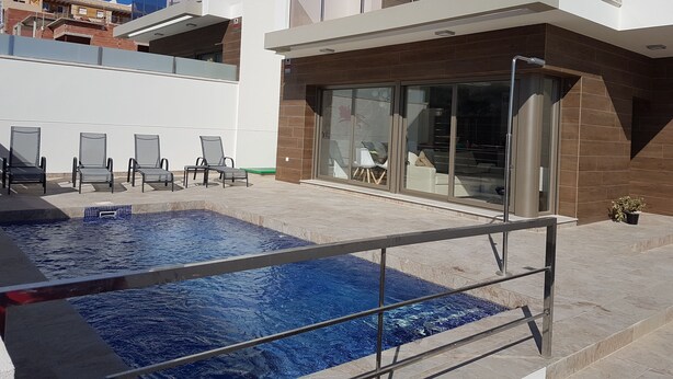 Un edificio moderno con piscina, zona de estar al aire libre y grandes ventanales.