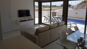 Una sala de estar moderna con un sofá, televisor y una mesa de vidrio con sillas.