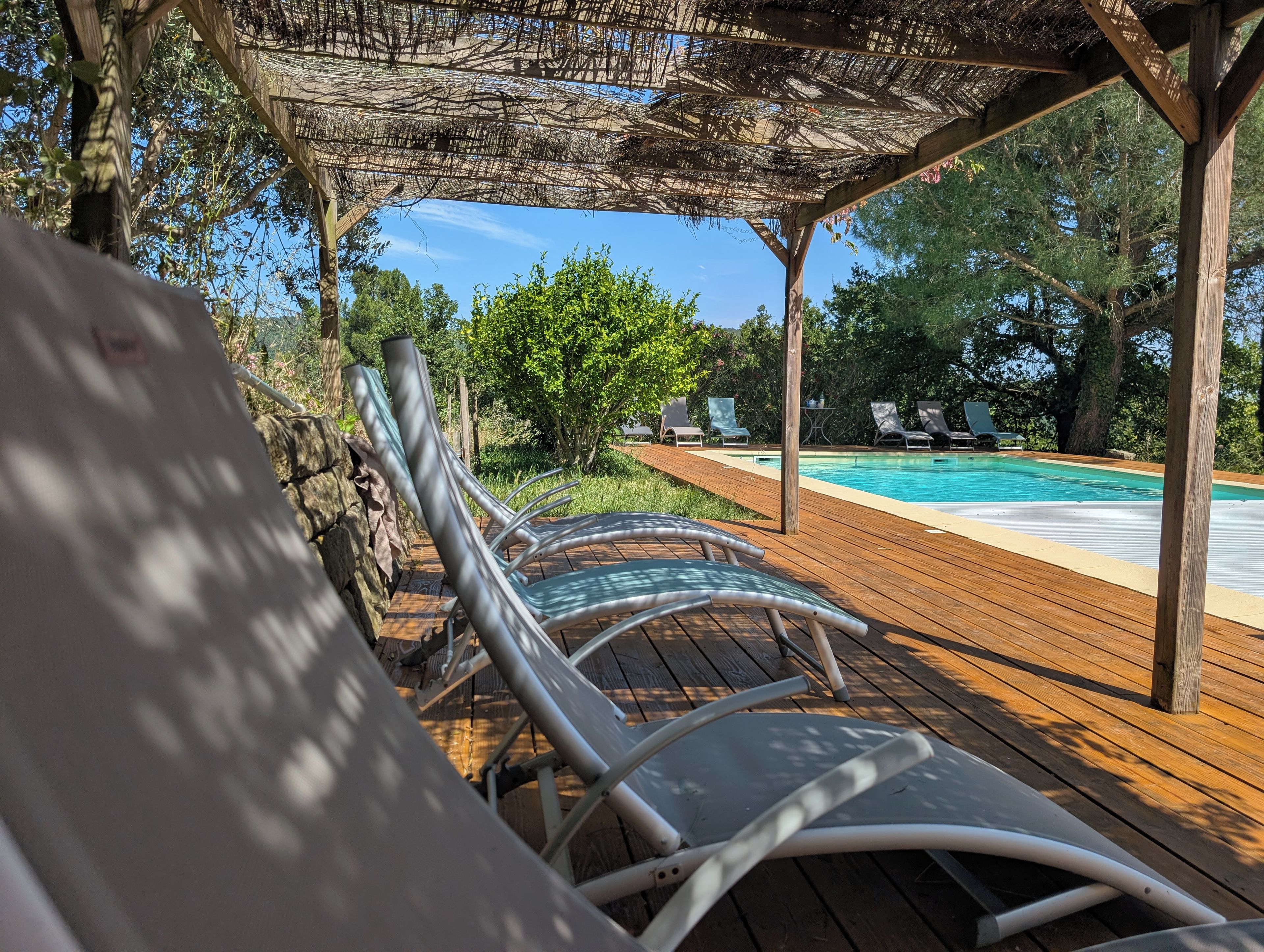 A wooden deck with lounge chairs and a pool.