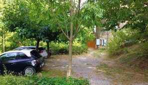 A gravel path leading to a parked car and a building with a stone wall. - Charming 16th-century country house, in Ardèche, with views of the Cévennes. (Chassiers)