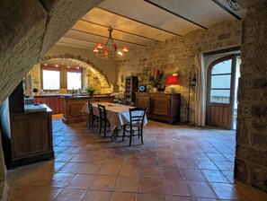Une cuisine rustique avec des murs en pierre, une table à manger en bois et un lustre.