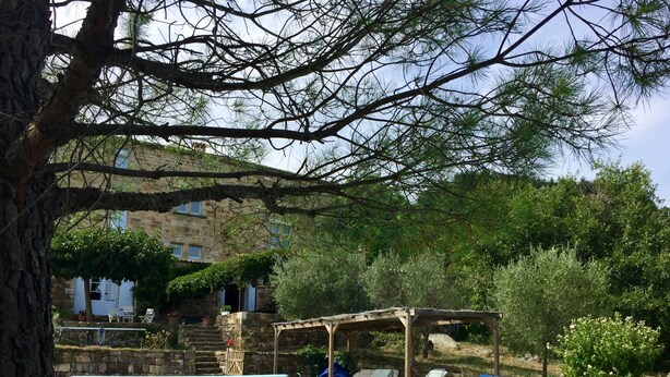 A pool area with lounge chairs and a pergola, surrounded by trees and a stone building. - Renovated farmhouse of the 16th, charming, south Ardèche (Chassiers)