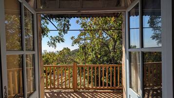 A wooden deck with a railing, a stone pathway, and a view of trees and sky.
