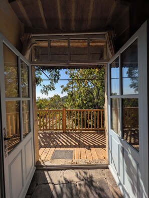 Une terrasse en bois avec une rambarde, un chemin de pierre et une vue sur les arbres et le ciel.