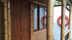 A wooden door with a window, surrounded by bamboo railings and a concrete base. - Apartamentos Martinez (San Andrés)