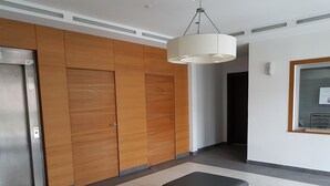 Un interior moderno con paneles de madera, un reposapiés negro y una lámpara en el techo.