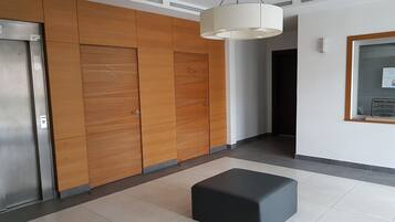 Un intérieur moderne avec un lambris en bois, un pouf noir et un luminaire suspendu au plafond.