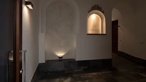 A hallway with a marble floor, a wooden door, and a wall-mounted light fixture. - Corral del Rey Terraza Sevilla Duplex, chillout terrace (Sevilla)