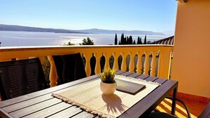 A balcony with a table, chairs, and a potted plant.