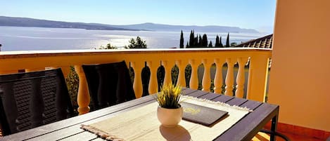 A balcony with a table, chairs, and a potted plant.