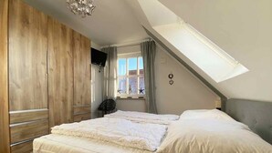 Une chambre à coucher avec un lit, une armoire en bois et un puits de lumière.