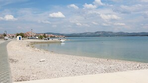 Ein Kiesstrand mit freiem Blick auf eine ferne Stadt und Berge.