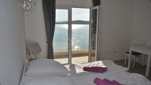 Ein Hotelzimmer mit zwei Betten, einem Schreibtisch und Blick auf das Meer.