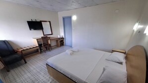 A hotel room with a bed, a desk, a chair, and a television on the wall. - Fun World Plaza Hotel (Nadi)