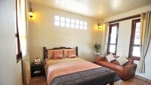 A bedroom with a bed, a sofa, a nightstand, and a window with curtains. - Bannraiphontawan (Nong Khai)