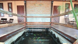 A brick wall with a wooden sign, a concrete floor, and a wooden deck with chairs. - Bannraiphontawan (Nong Khai)