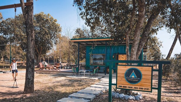 A campsite with a wooden signboard, picnic tables, and a covered area. - Bannraiphontawan (Nong Khai)