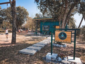 A campsite with a wooden signboard, picnic tables, and a covered area. - Bannraiphontawan (Nong Khai)