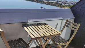 A balcony with a wooden table and chairs, overlooking a marina with boats and a dock. -  MORBIHAN - SPLENDID VIEW ON THE RIA AND THE BAR OF ETEL - 15 METERS FROM THE BEACH  (Étel)