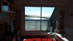 A living room with a large sliding glass door leading to a balcony with a view of the sea. -  MORBIHAN - SPLENDID VIEW ON THE RIA AND THE BAR OF ETEL - 15 METERS FROM THE BEACH  (Étel)