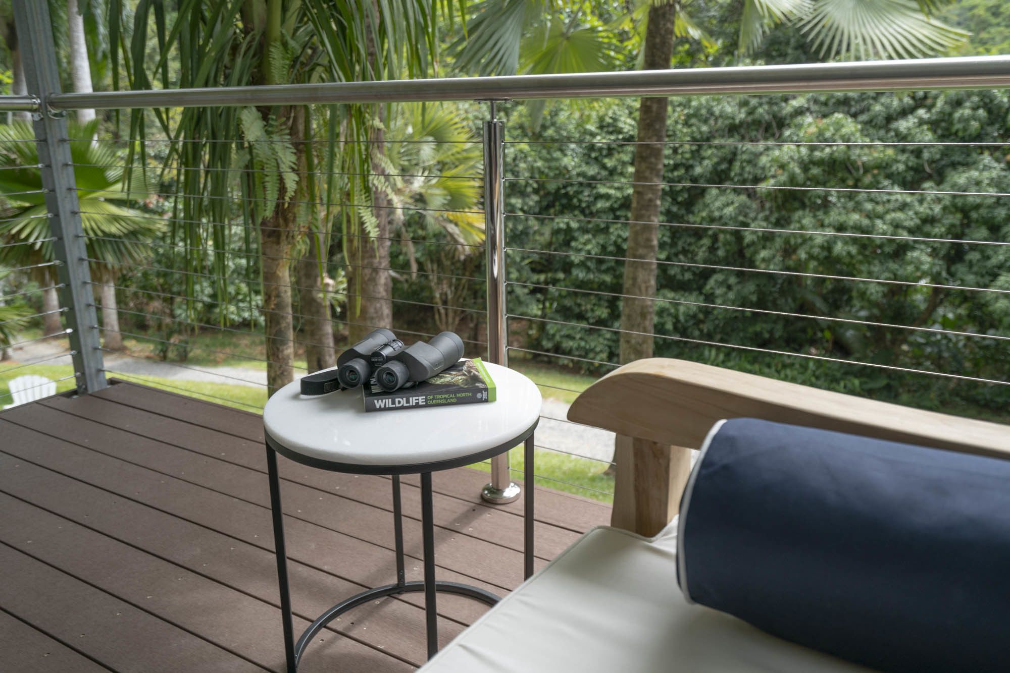 A balcony with a table holding binoculars and a book titled "Wildlife of Tropical Queensland".