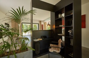 A modern office space with a desk, chair, bookshelf, and potted plants.
