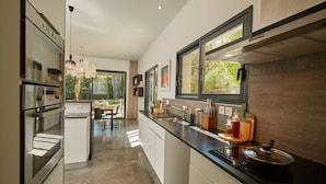 Een moderne keuken met roestvrijstalen apparatuur, een zwart aanrecht en een raam met uitzicht op groen.