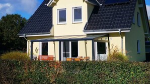 A two-story house with a sloped roof, a covered porch, and solar panels. - NEW 2018 holiday home exclusively near the beach, sauna, fireplace, free WiFi, garden (Wiek /Rügen)