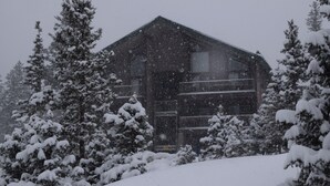 A snow-covered building with a symmetrical facade, surrounded by snow-laden trees.