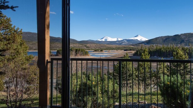 Ein Balkon mit Blick auf einen mit Schnee bedeckten Berg, einen Fluss und den umliegenden Wald.